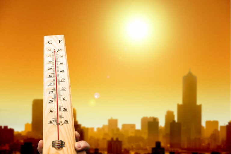 heat wave in the city and hand showing thermometer for high temperature