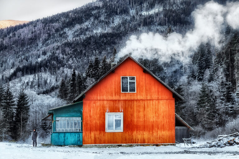 In the high mountains, among the wild forest huts located shelters hunters and loggers and smoke over chimney.