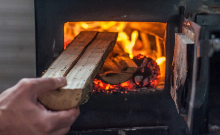 Man putting log to wood burning stove. Close up