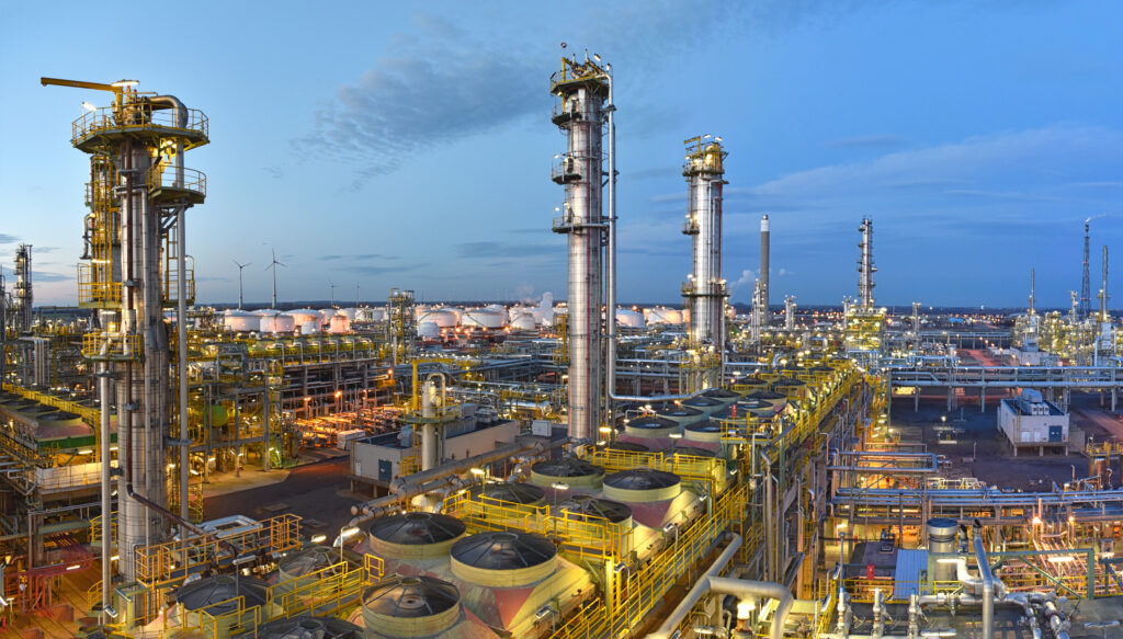 refinery – chemical factory at night with buildings, pipelines and lighting – industrial plant