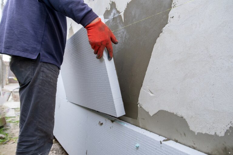 Construction worker installing styrofoam insulation sheets on ho