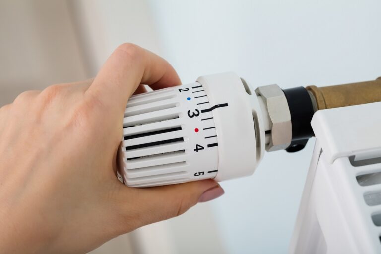 Woman’s Hand Adjusting Thermostat Valve