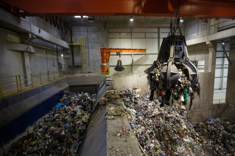 Mechanical claw hand grabbing pile of mixed waste