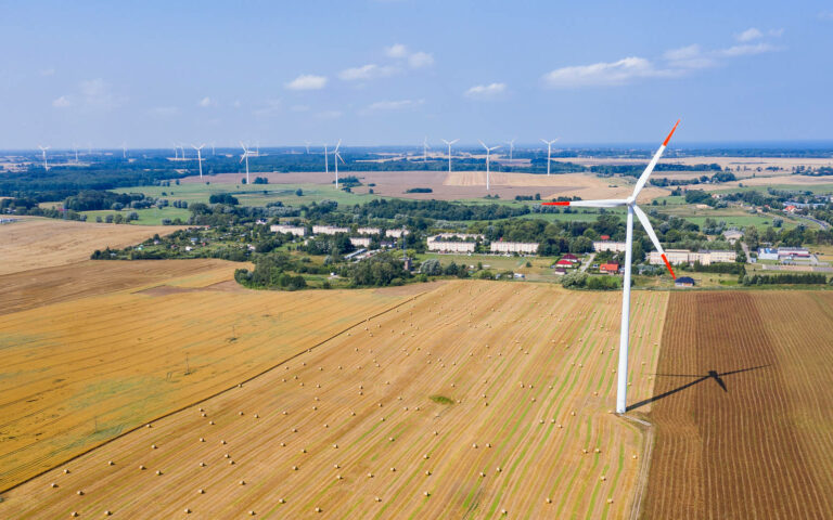 wind turbine on the arable field. straw bales in the field