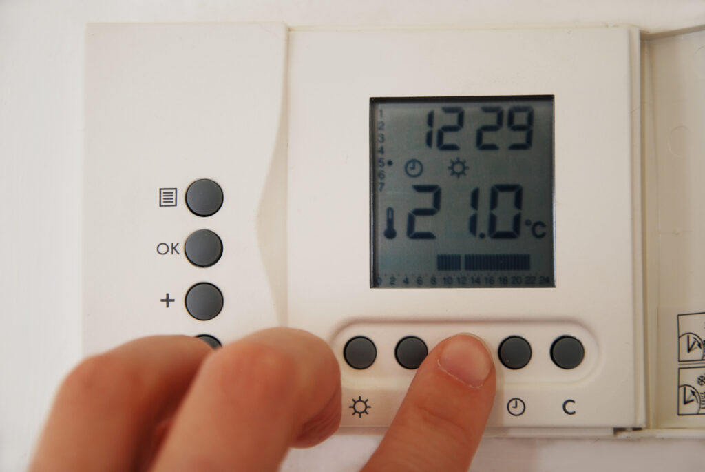 hand setting the temperature of the gas heating thermostat