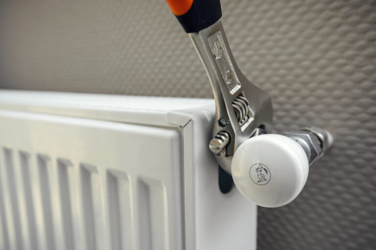 Close up of male plumber installing radiator with wrench