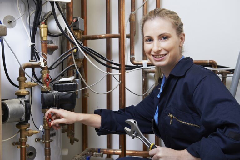 Female Plumber Working On Central Heating Boiler