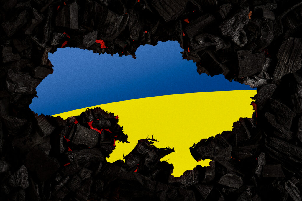 Ukraine against the background of burnt coals. The colors of the Ukrainian flag are blue and yellow on a dark background.