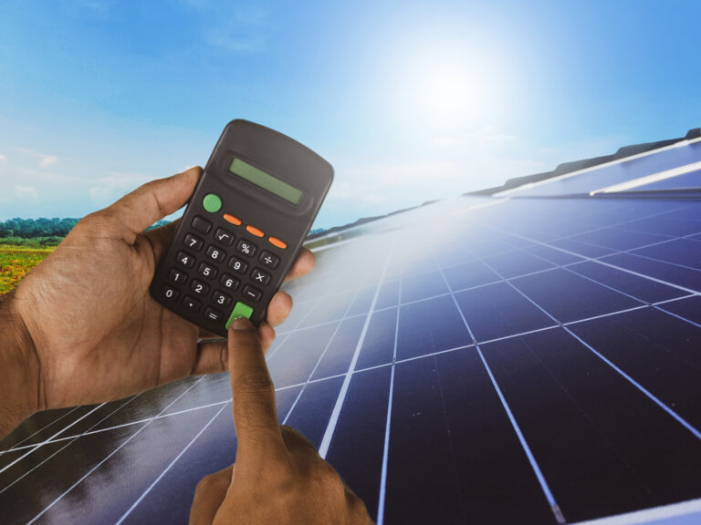 Holding a calculator on a solar panel photovoltaic installation