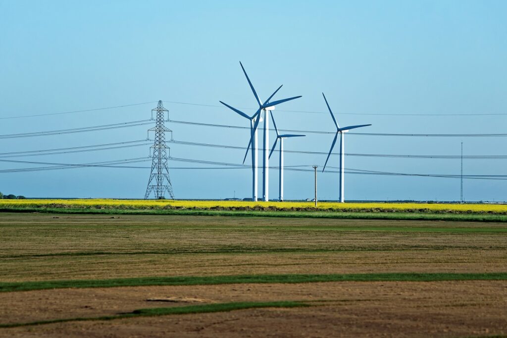 Meadow with Wind turbines generating electricity and electric po