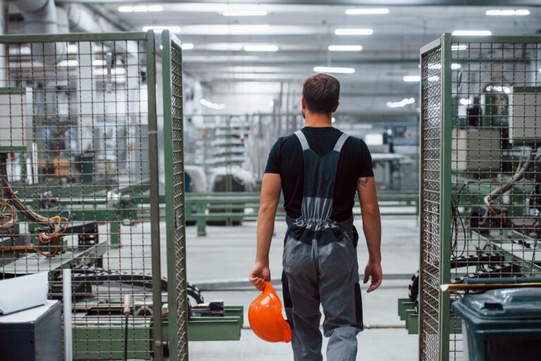 Industrial worker indoors in factory. Young technician with orange hard hat