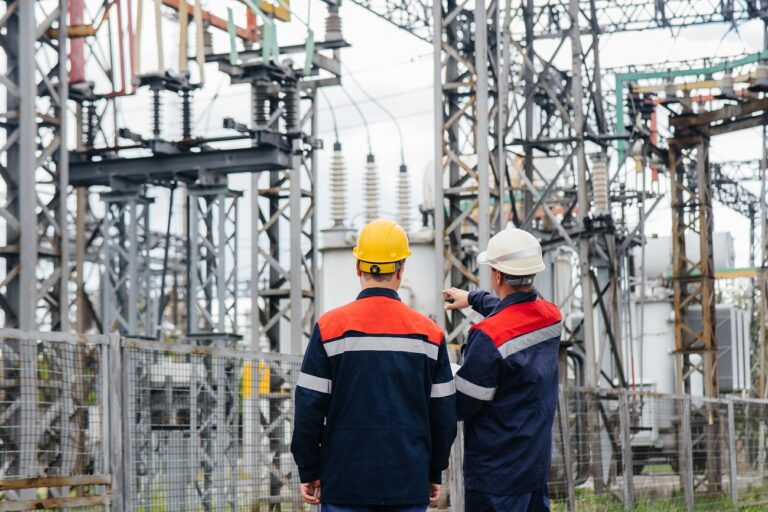 Two specialist electrical substation engineers inspect modern high-voltage equipment. Energy. Industry.
