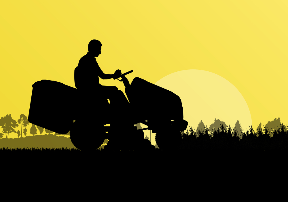 Man with lawn mower tractor cutting grass in field landscape bac