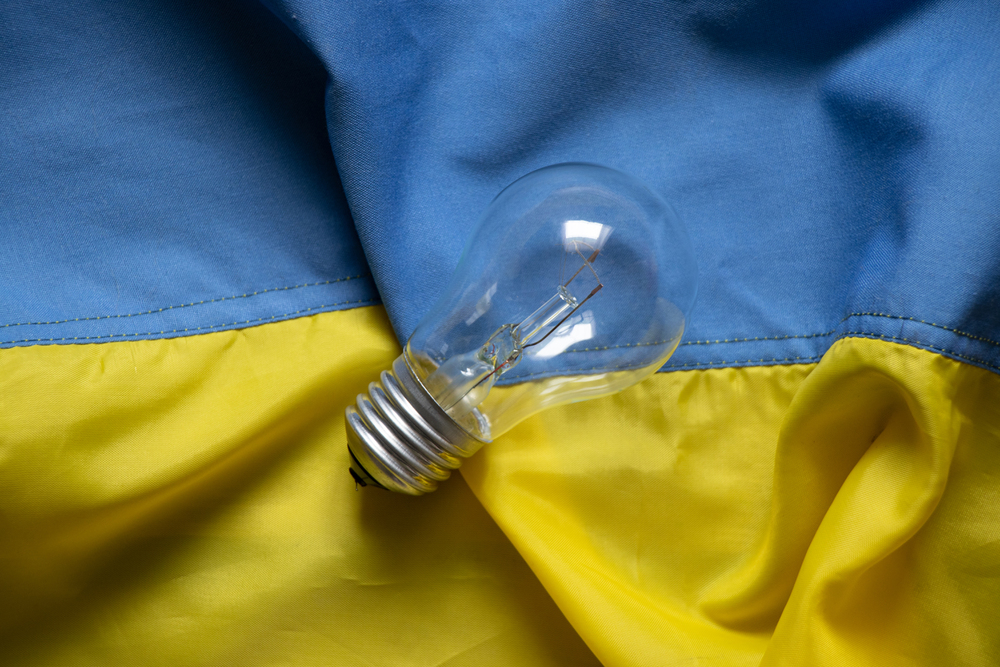 An incandescent lamp lies on the flags of Ukraine, people without light in Ukraine due to Russian missile attacks, war, crisis 2023